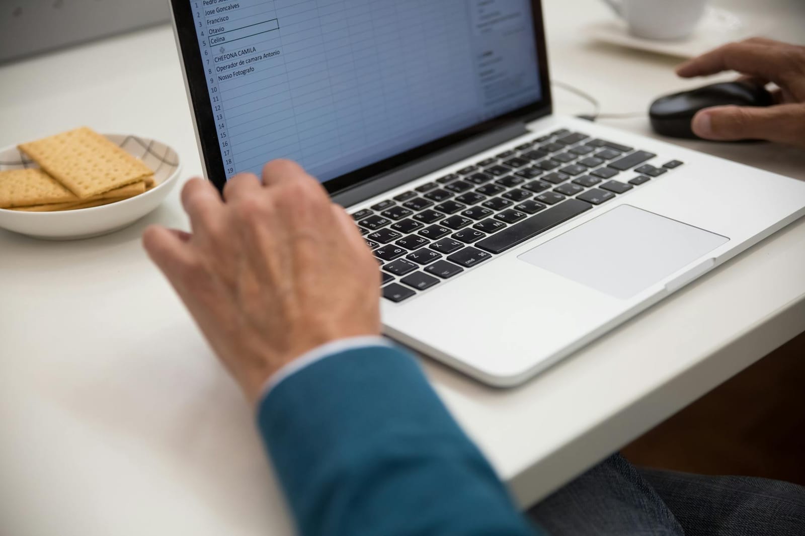 Laptop with a spreadsheet open beside a cup of coffee