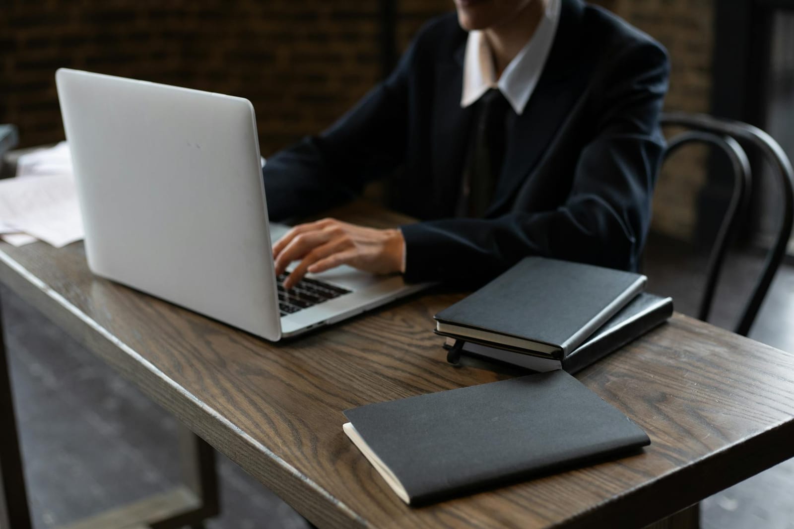 Person working at a laptop with a notebook beside them